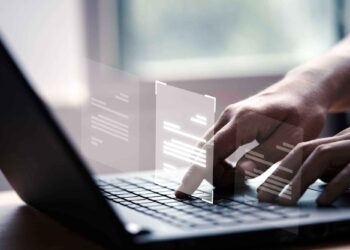 Hands typing on a laptop keyboard with digital interface graphics representing virtual documents floating above.